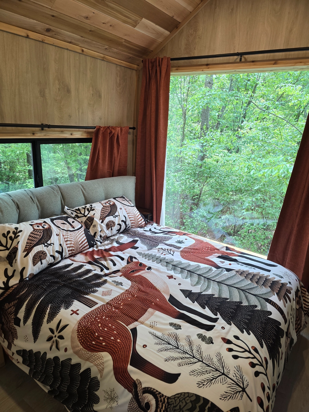 Bed at Cabin @28 with a large picture window looking out into the forest