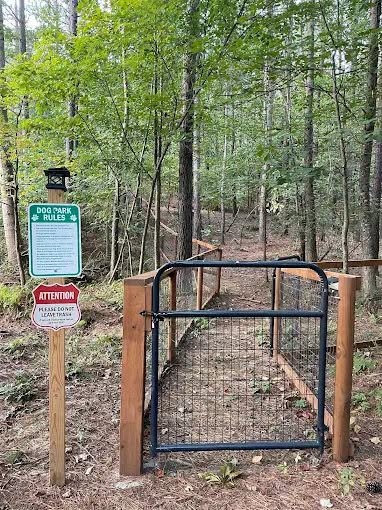 Fenced dog park entrance gate in the woods at Sasquatch Farm RV Park