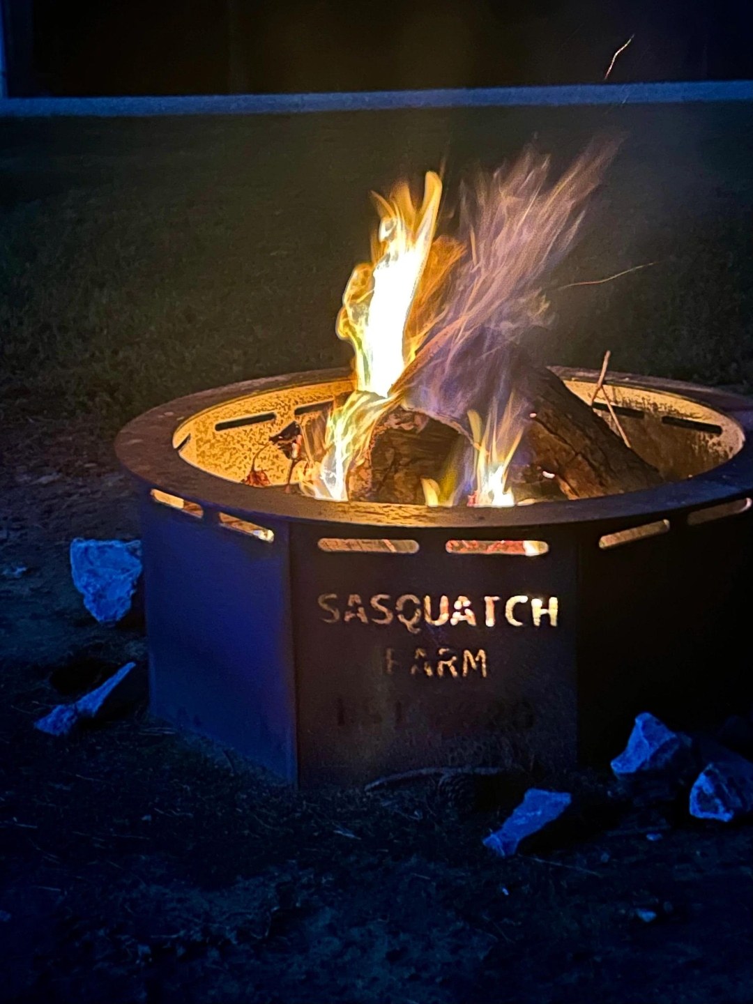 Branded Sasquatch Farm fire pit burning at night