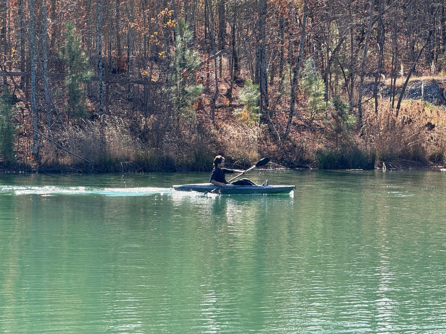 Kayaker paddling across the fishing lake in fall color at Sasquatch Farm RV Park